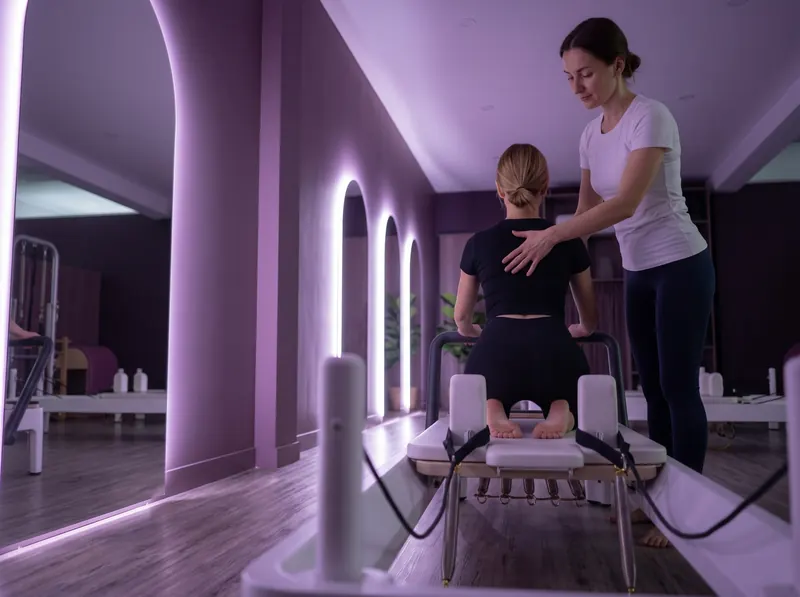 Group pilates in Limassol: a coach corrects posture on the reformer